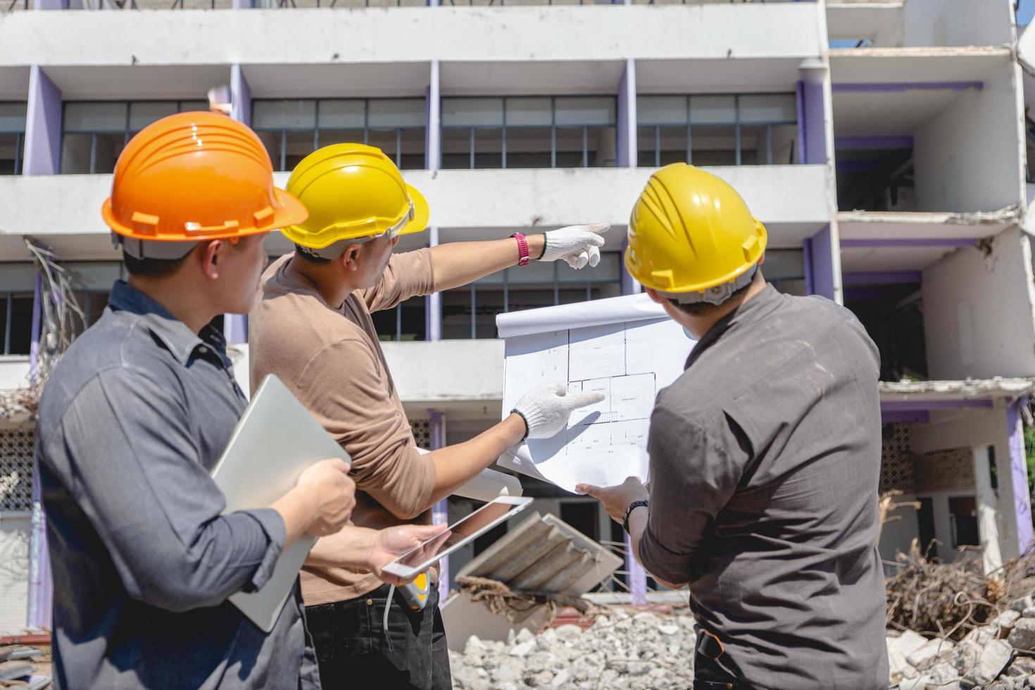 l'équipe d'ingénieurs et le travailleur vérifient le plan de construction d'émolitions et inspectent sur le site. photo