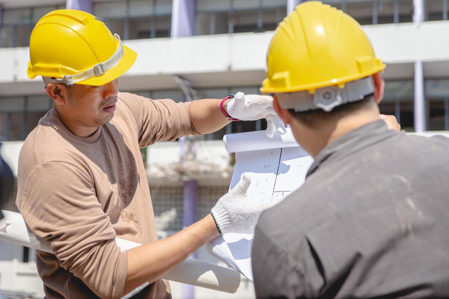 l'équipe d'ingénieurs et le travailleur vérifient le plan de construction d'émolitions et inspectent sur le site. photo