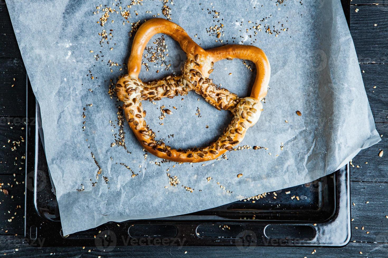 bretzels mous maison fraîchement préparés. différents types de bagels cuits au four avec des graines sur fond noir. photo