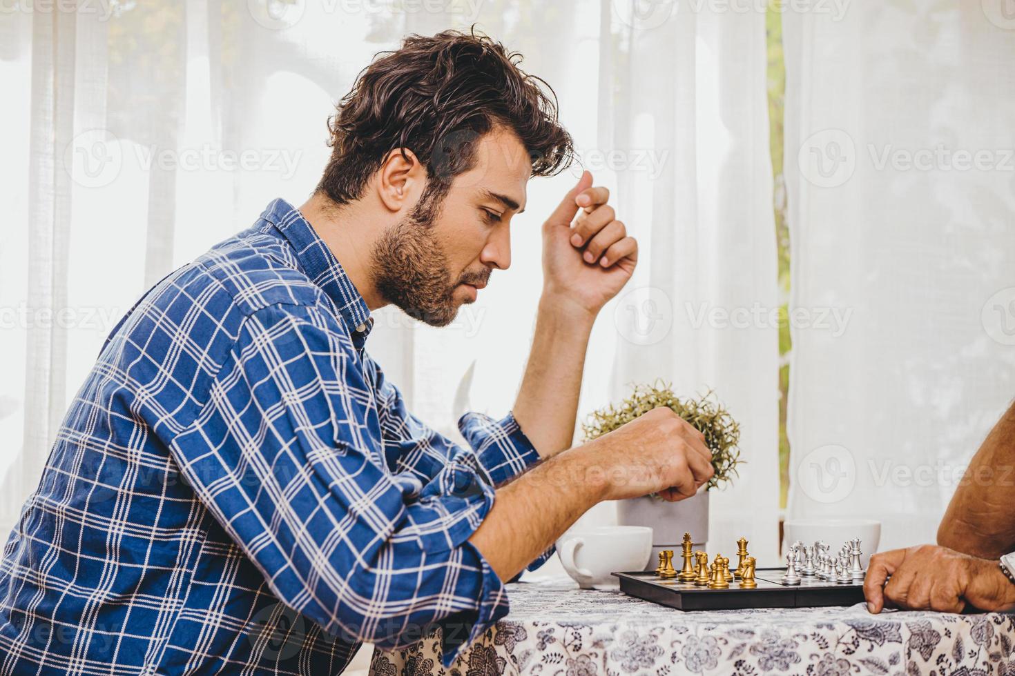 homme latin jouant au jeu d'échecs à la maison pour des activités de vacances avec sa famille, il pense et a l'air sérieux photo