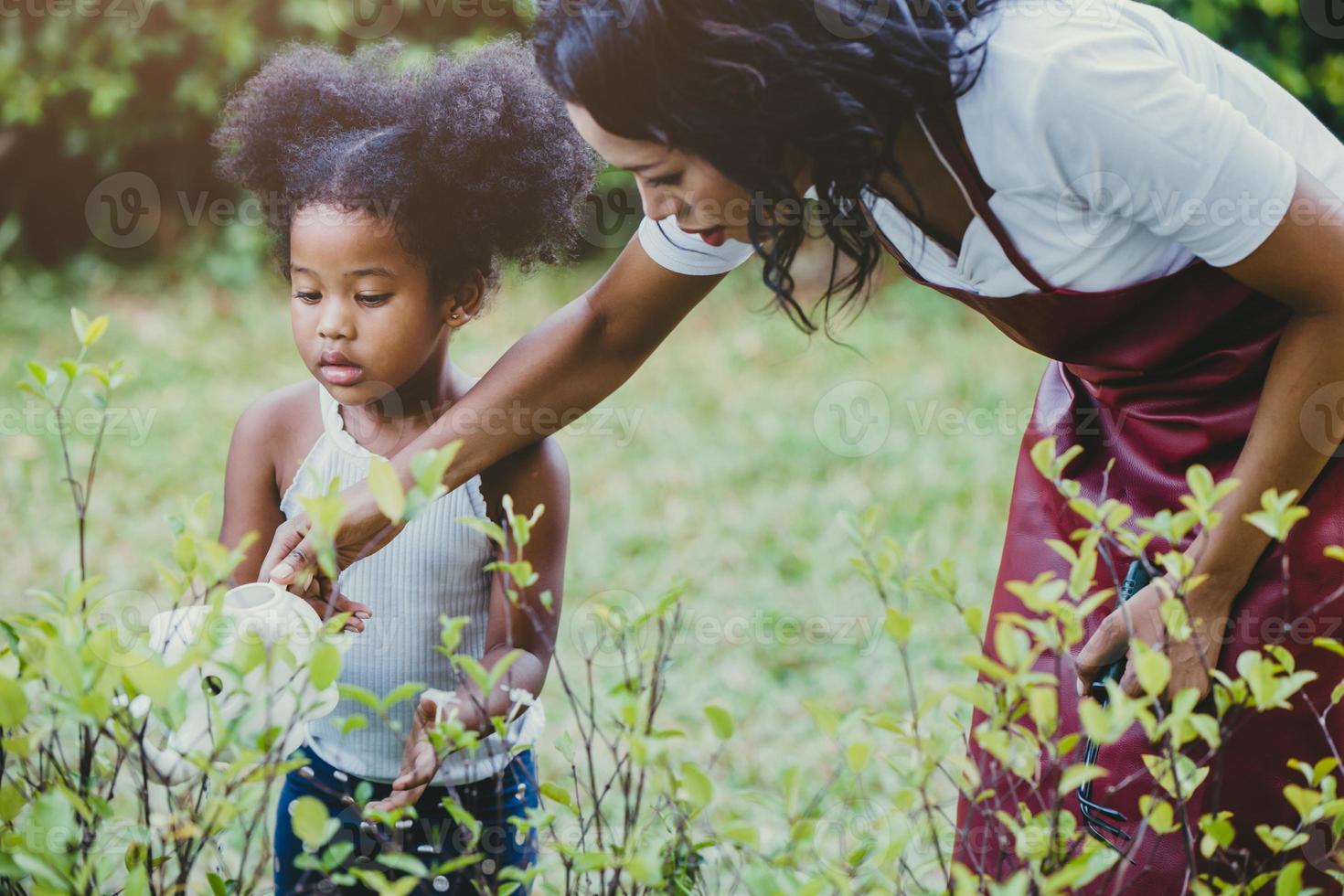 famille beau jardinage arrosage activité de plantes vertes avec les enfants pendant le séjour à la maison pour réduire l'épidémie de coronavirus. enfants arrosant la plante à l'arrière-cour. photo