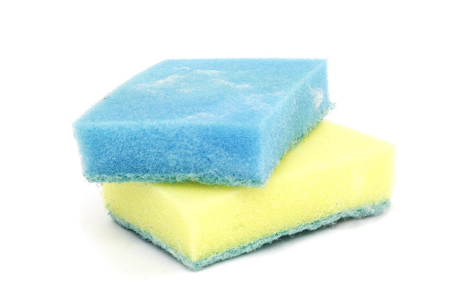 Une éponge bleue avec une solution de nettoyage en mousse et une nouvelle éponge jaune en dessous isolée sur fond blanc photo