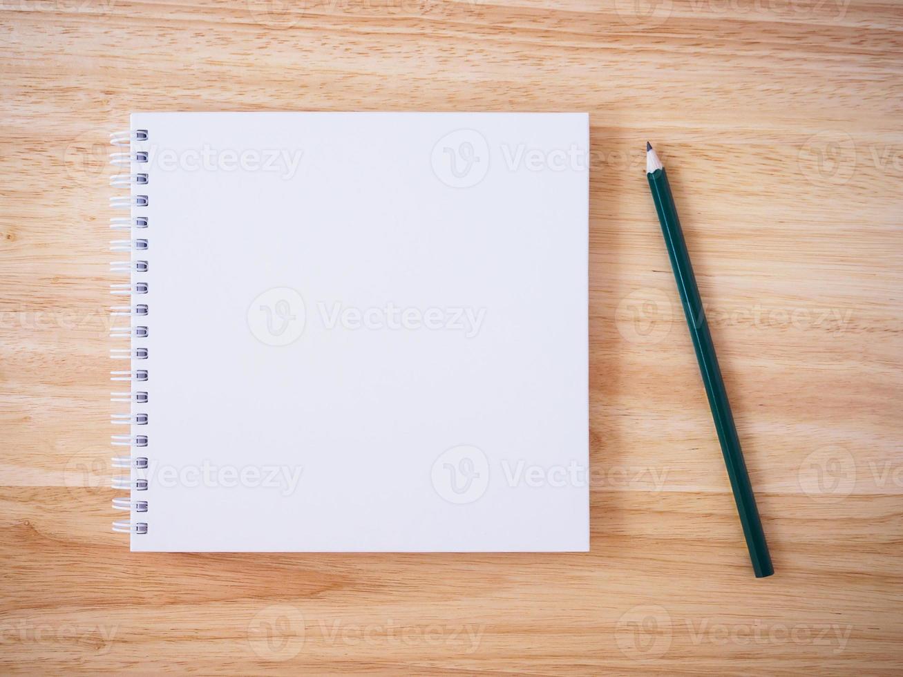 vue de dessus de cahier à couverture blanche avec un crayon sur un bureau en bois brun photo