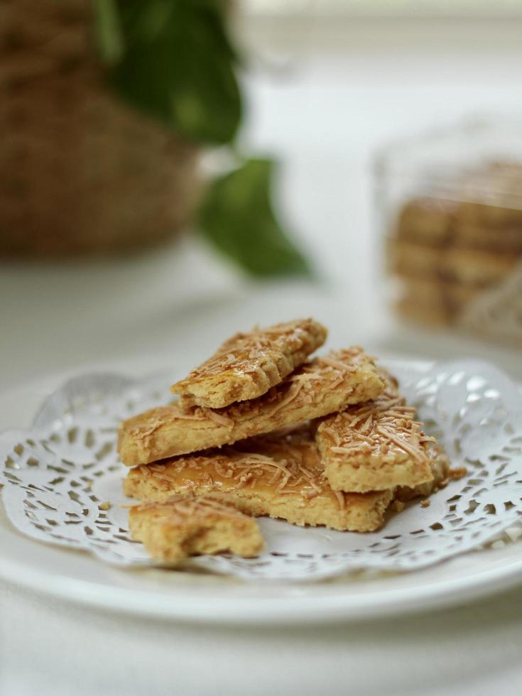 Angle de vue des bâtonnets de fromage indonésien appelé kaastengel, sur papier rustique blanc, avec plante floue photo