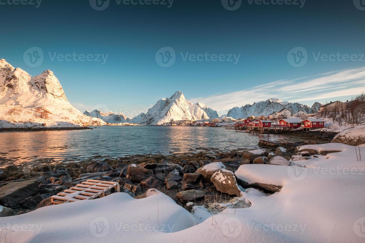 village scandinave dans la chaîne de montagnes enneigées sur le littoral photo