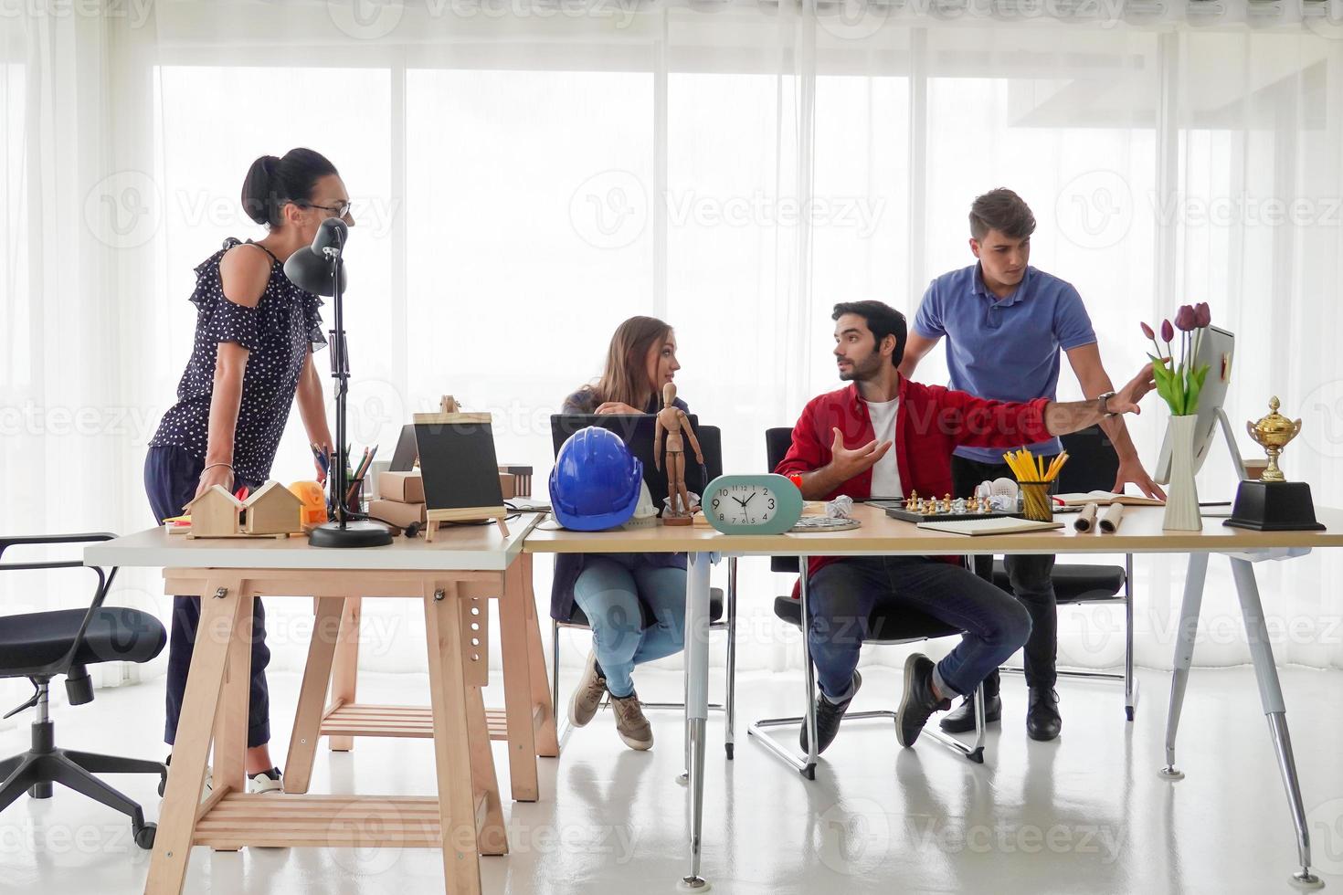 groupe diversifié de jeunes gens d'affaires discutant d'un projet de travail assis ensemble à une table dans un bureau moderne. concept de coworking photo