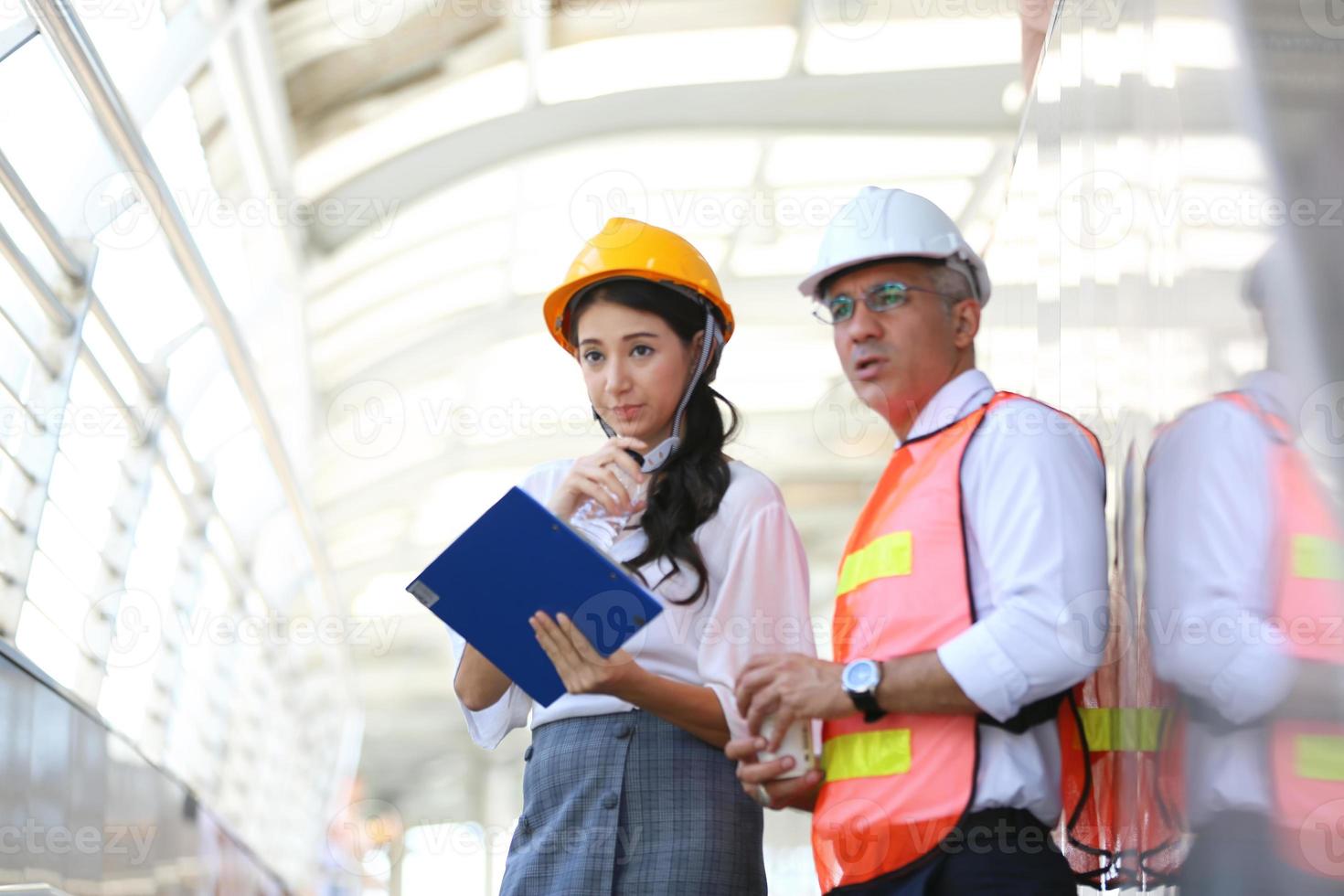 l'ingénieur et la femme d'affaires vérifient le presse-papiers sur le chantier de construction. le concept d'ingénierie, de construction, de vie urbaine et d'avenir. photo