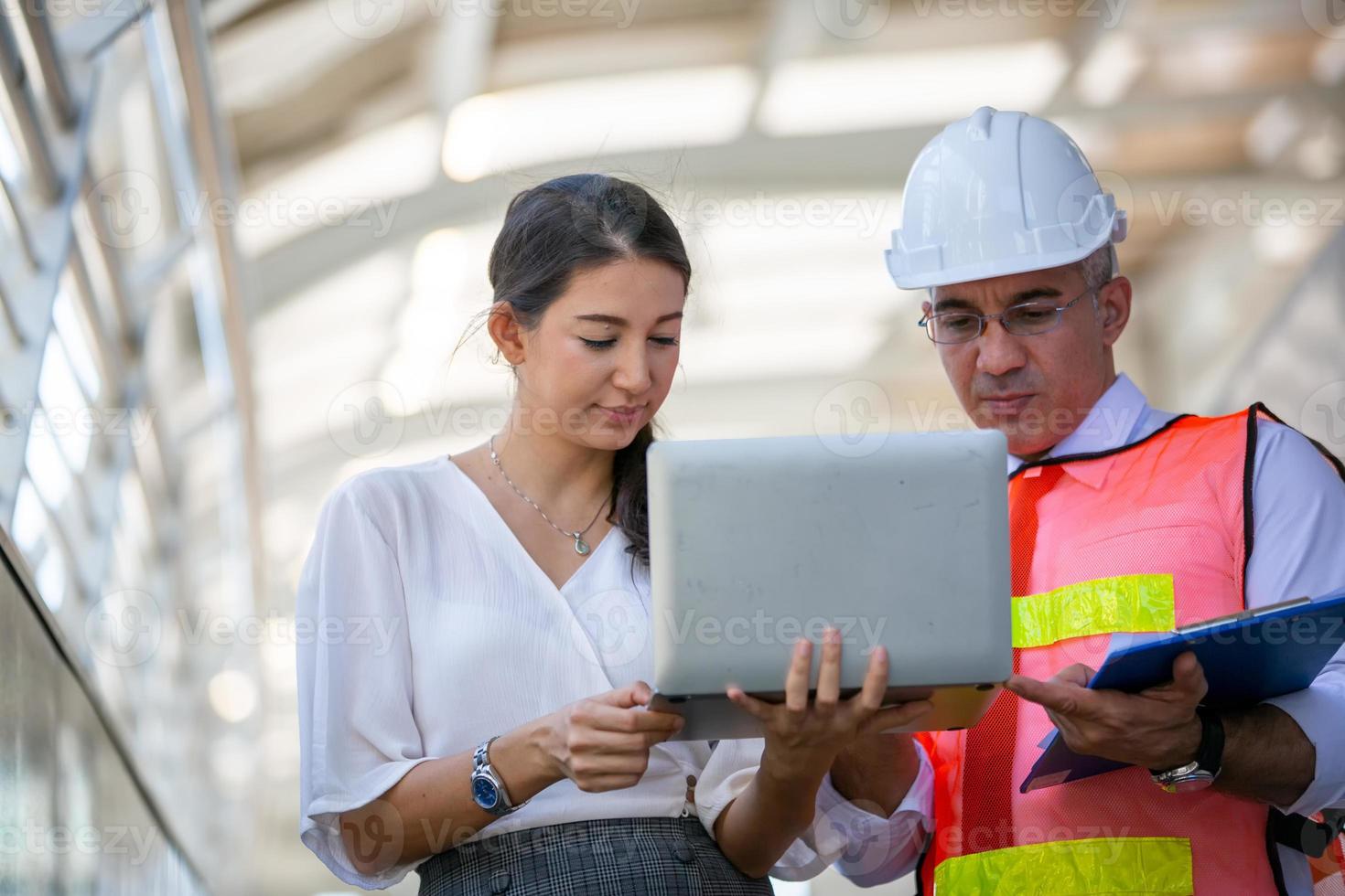 l'ingénieur et la femme d'affaires vérifient le presse-papiers sur le chantier de construction. le concept d'ingénierie, de construction, de vie urbaine et d'avenir. photo