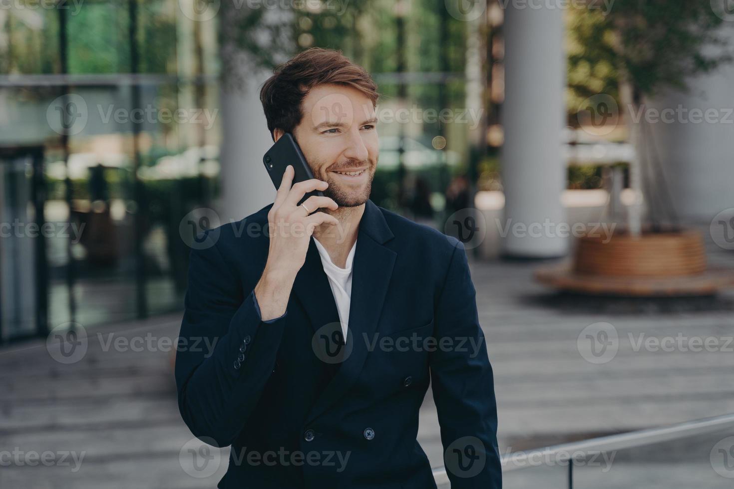 un homme confiant, un entrepreneur vêtu de vêtements formels, passe un appel téléphonique en itinérance photo