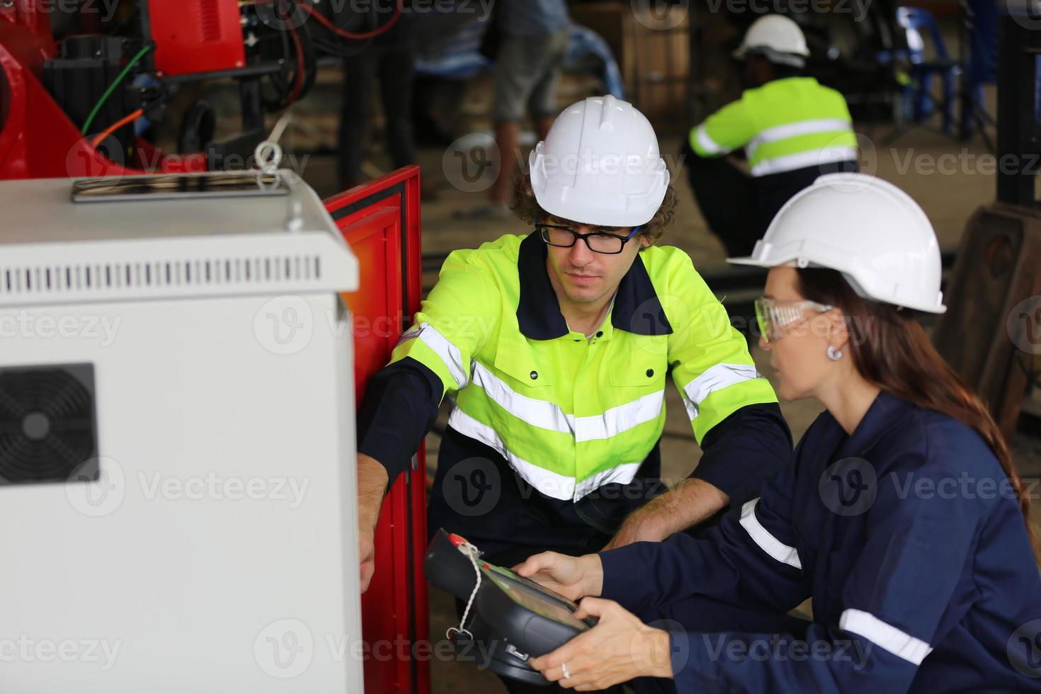 trois ingénieurs et ouvriers multiculturels de l'industrie lourde dans un bras de robot automatique à contrôle uniforme pour l'utilisation en usine. l'entrepreneur industriel féminin utilise une tablette. photo