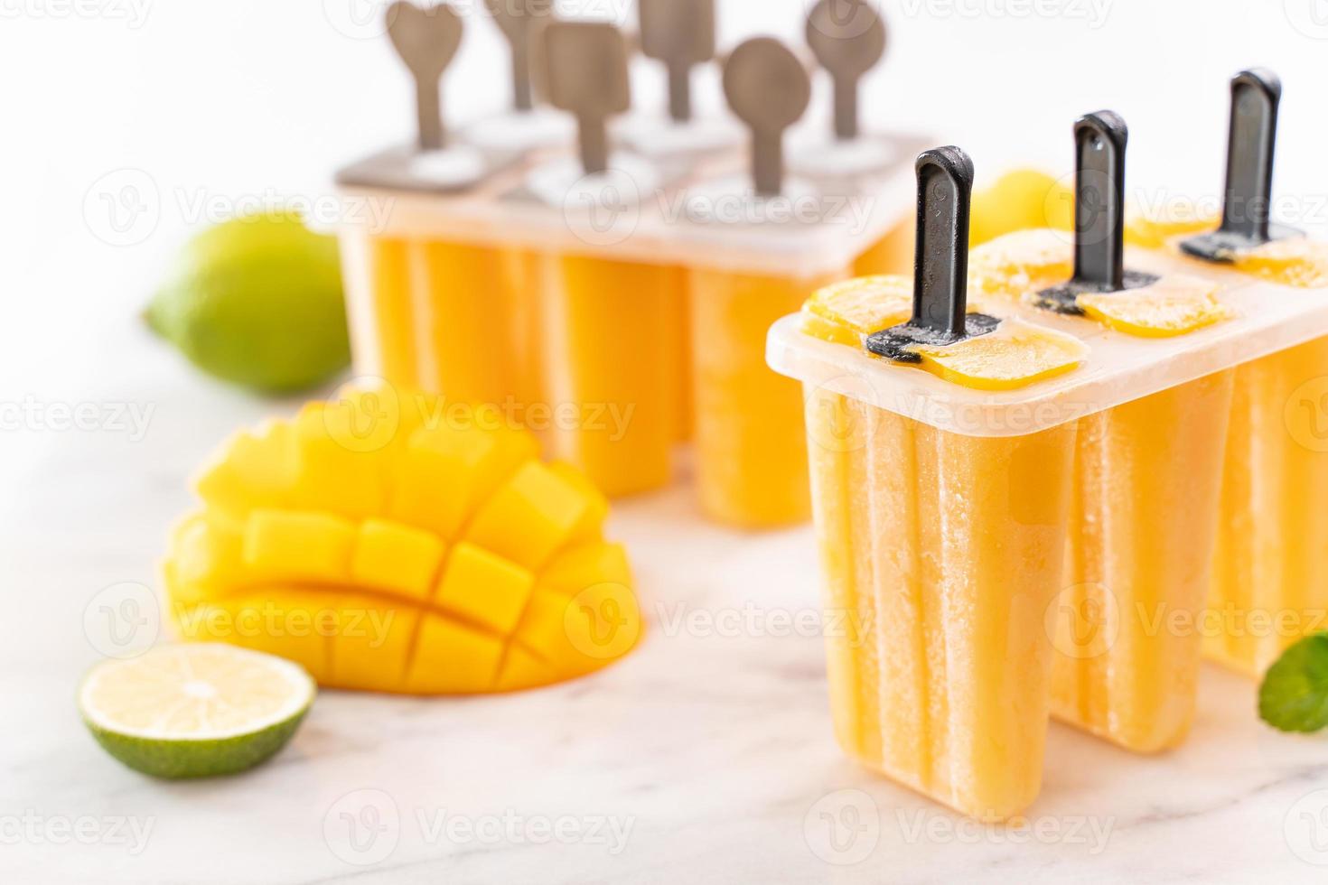 Glace popsicle aux fruits de mangue fraîche dans la boîte de mise en forme en plastique sur une table en marbre clair. conception de produits de concept d'humeur d'été, gros plan. photo