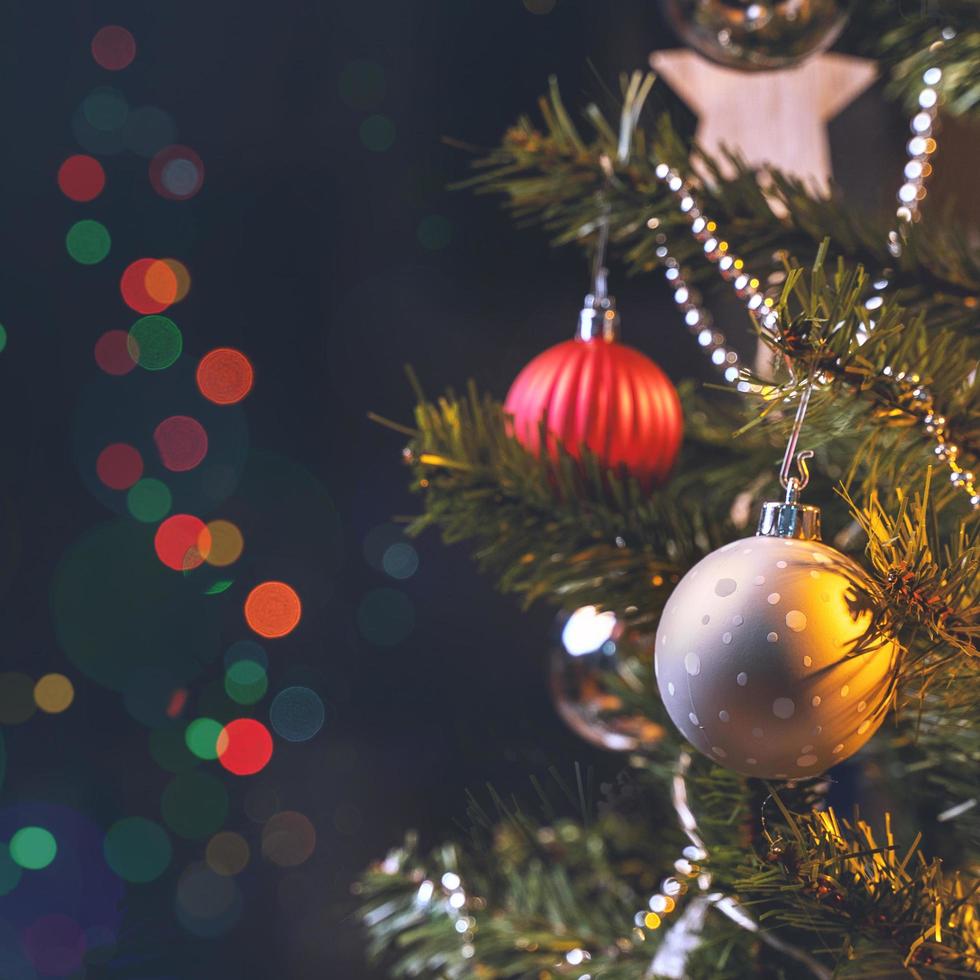 beau concept de décor de noël, babiole accrochée à l'arbre de noël avec une tache lumineuse étincelante, fond noir foncé flou, détail macro, gros plan. photo