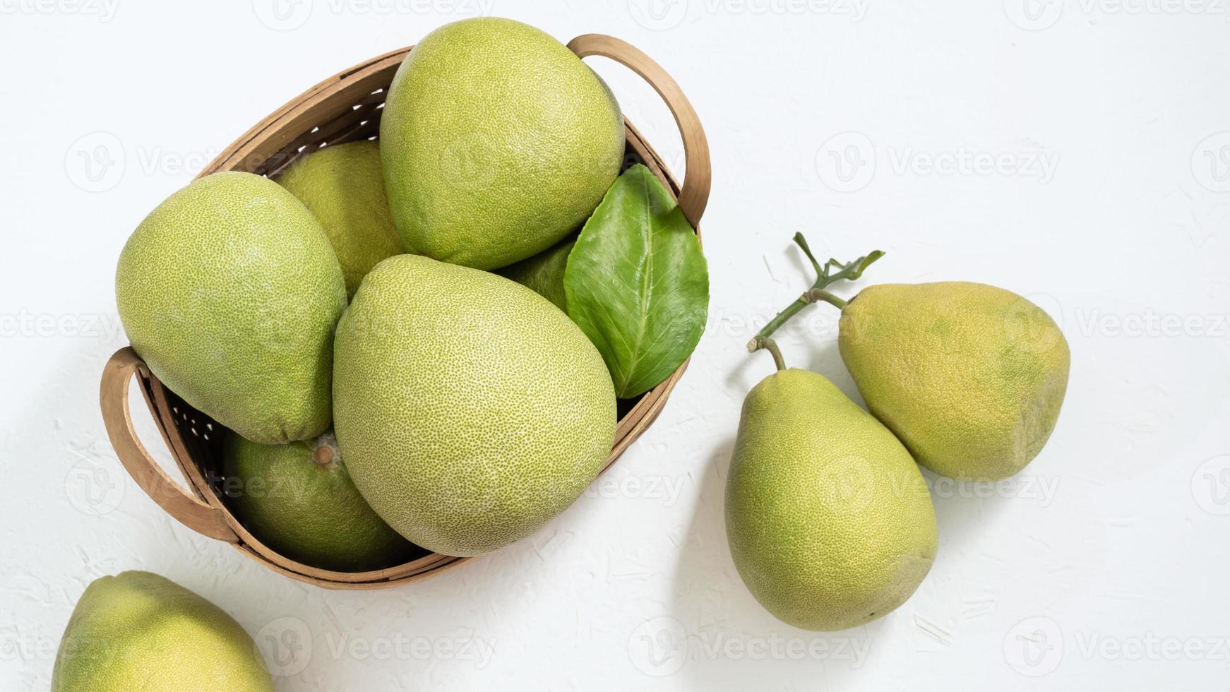 pomelo frais, pomelo, pamplemousse, shaddock sur fond de ciment blanc dans un panier en bambou. fruits de saison d'automne, vue de dessus, mise à plat, prise de vue sur table. photo