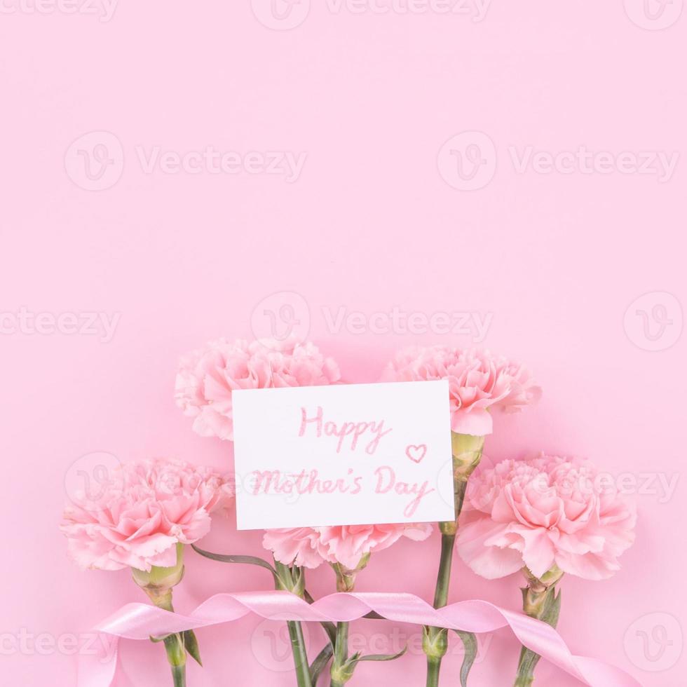 beau bouquet de fleurs d'oeillet frais et élégant avec carte-cadeau de remerciement de salutation blanche isolée sur fond de couleur rose vif, vue de dessus, concept de mise à plat. photo