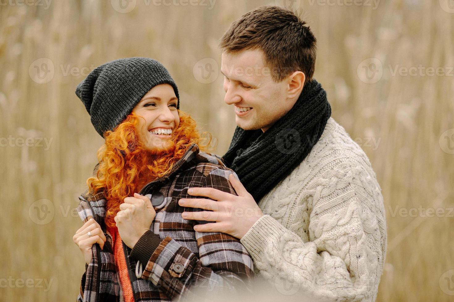 couple heureux amoureux en automne. un homme moustachu aux cheveux bouclés et une femme aux cheveux roux dans des vestes en cuir et des jeans s'embrassent tendrement. fille fait des paumes de coeur photo