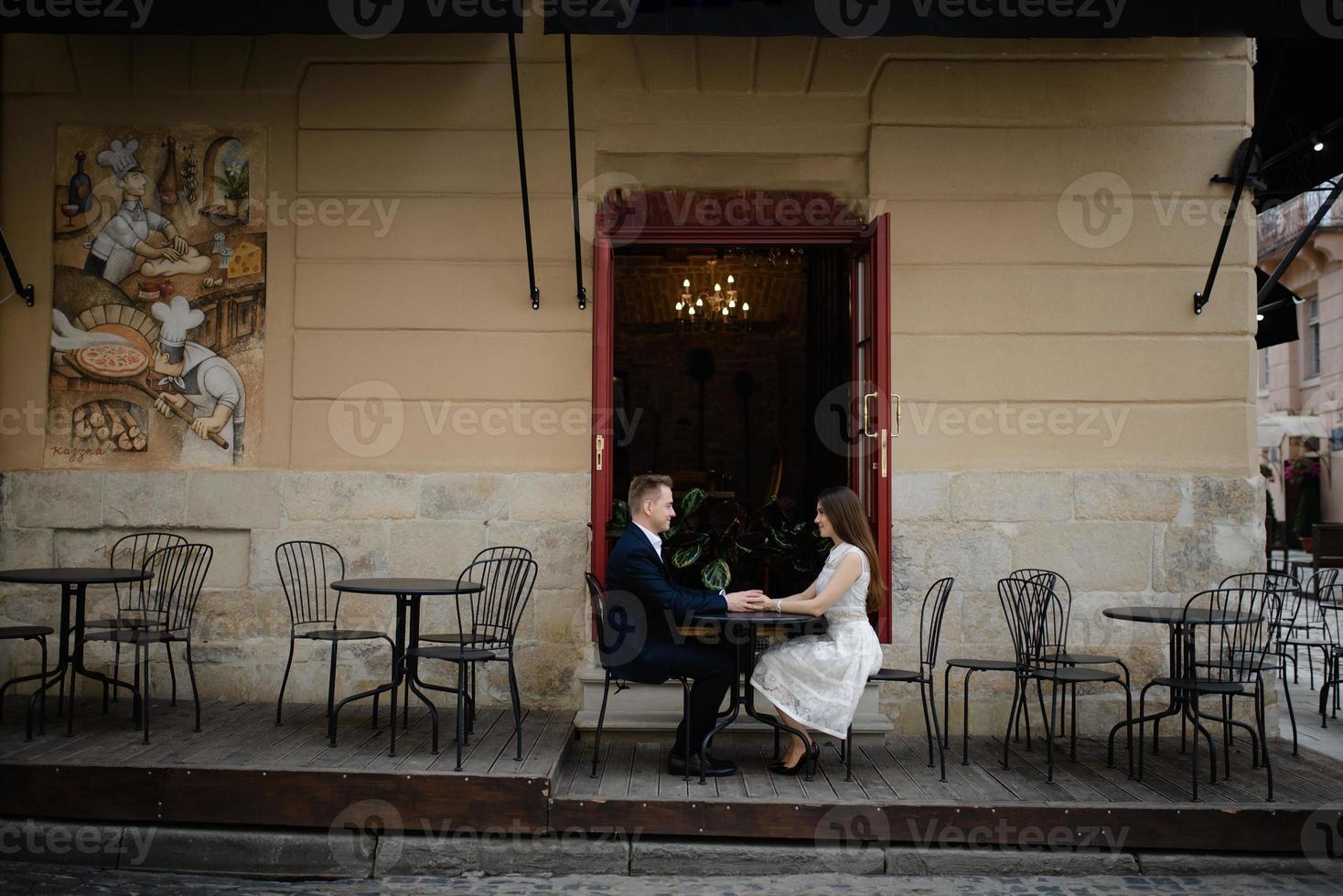 un couple marié heureux est en lune de miel, ayant un brunch dans un joli café avec un intérieur moderne, une terrasse d'été lumineuse avec de belles plantes vertes photo