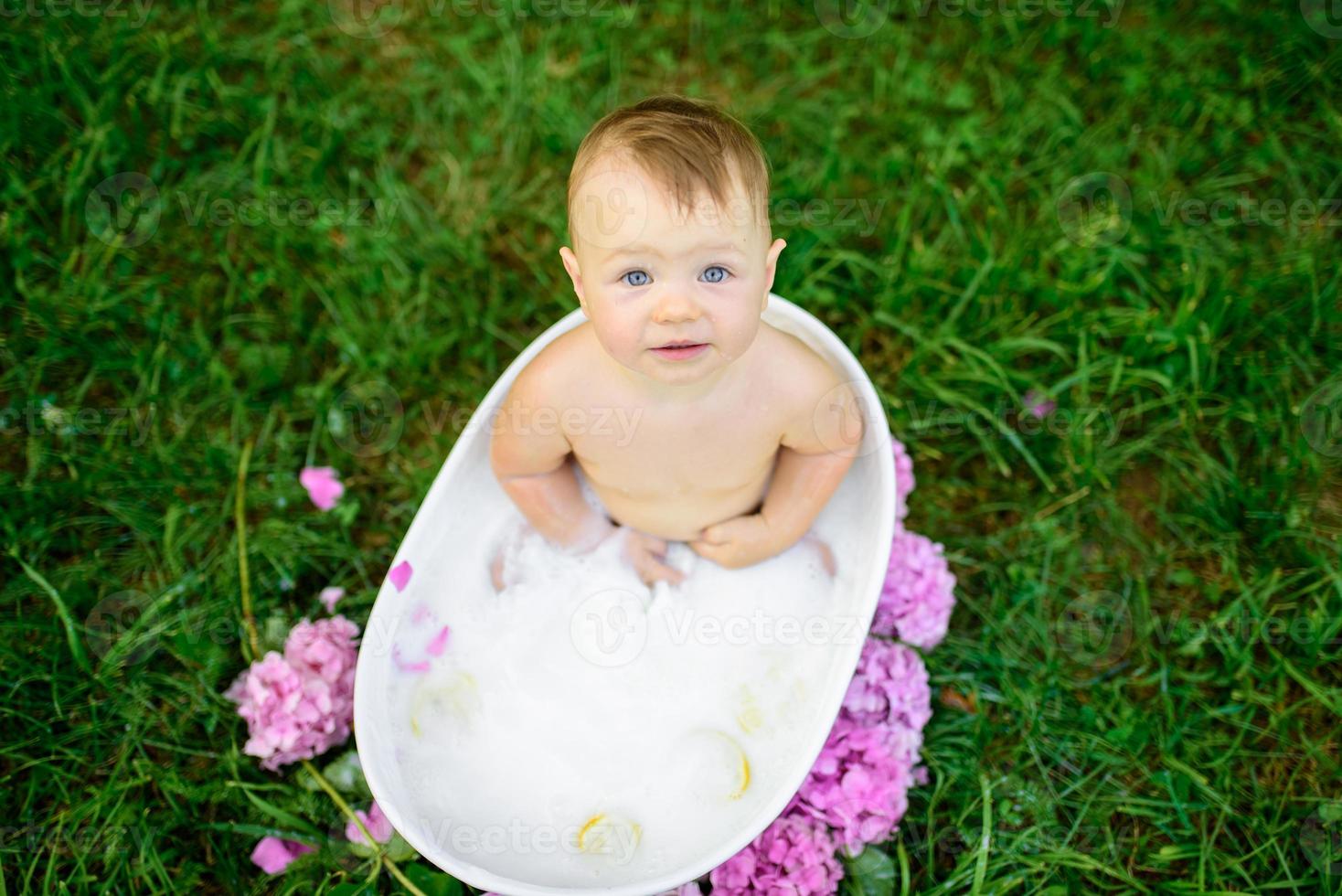 petite fille se baigne dans un bain de lait dans le parc. la fille s'amuse en été. photo