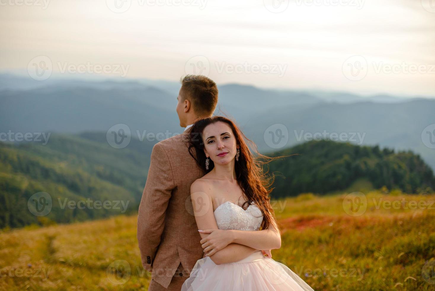 élégant jeune mariée et le marié se tiennent en bateau sur fond de ciel nuageux mer et montagnes du monténégro photo