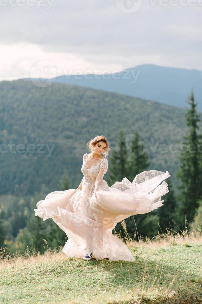 Whirling bride holding voile jupe de robe de mariée à forêt de pins photo