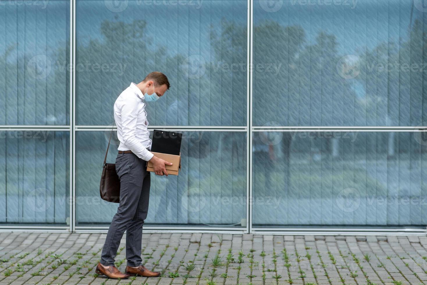 l'employé de bureau licencié est tombé à genoux et s'est couvert le visage à cause du stress. devant lui se trouve une boîte en carton avec du papier à lettres. l'homme est mécontent en raison d'une réduction du robot. photo