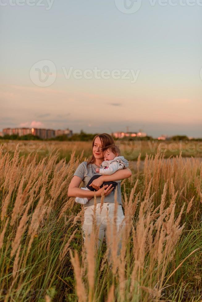 une mère se promène dans le champ avec sa petite fille dans ses bras. photo