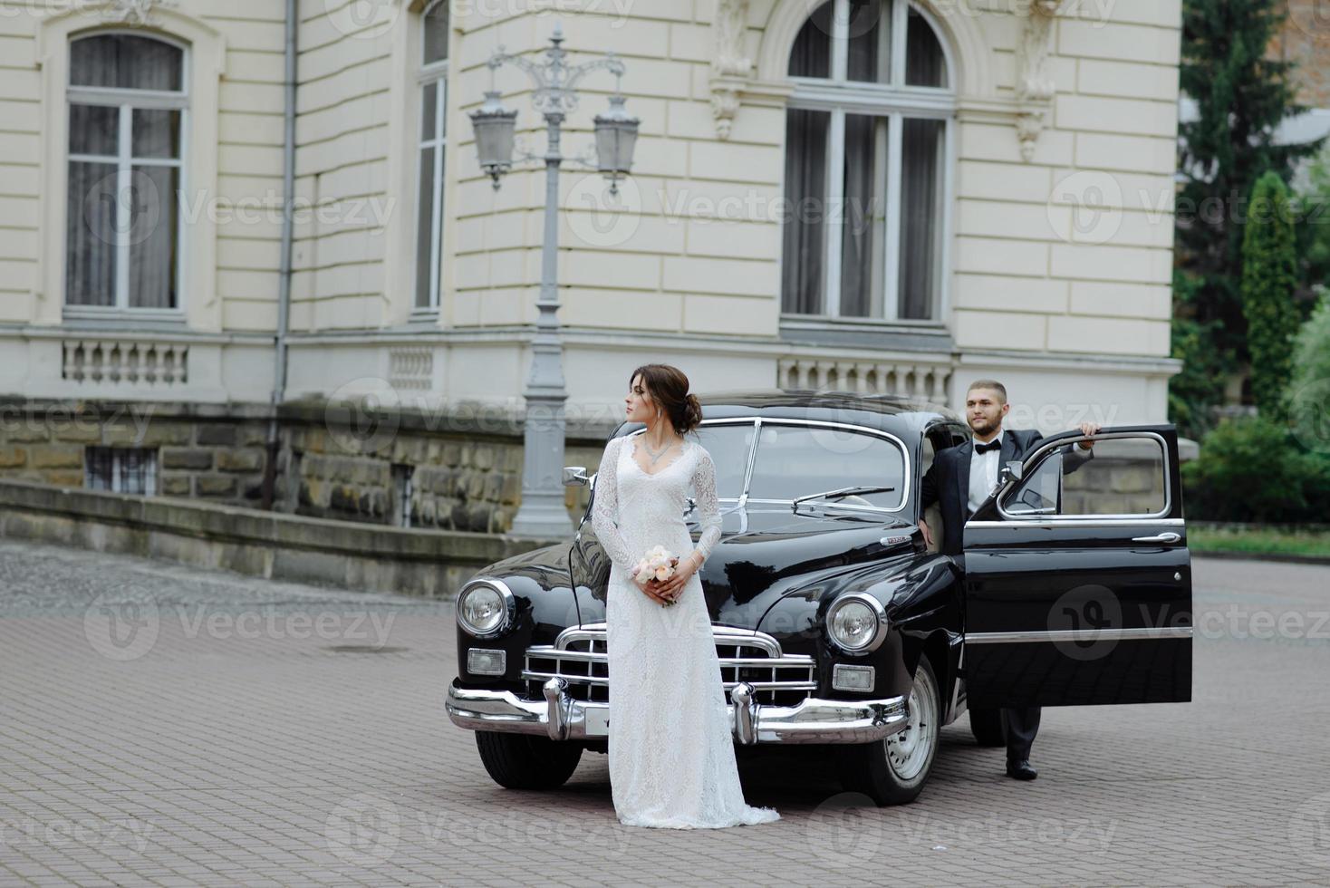 Heureux couple de mariage de luxe s'embrasser et s'embrasser près de rétro avec voiture bouquet en automne photo
