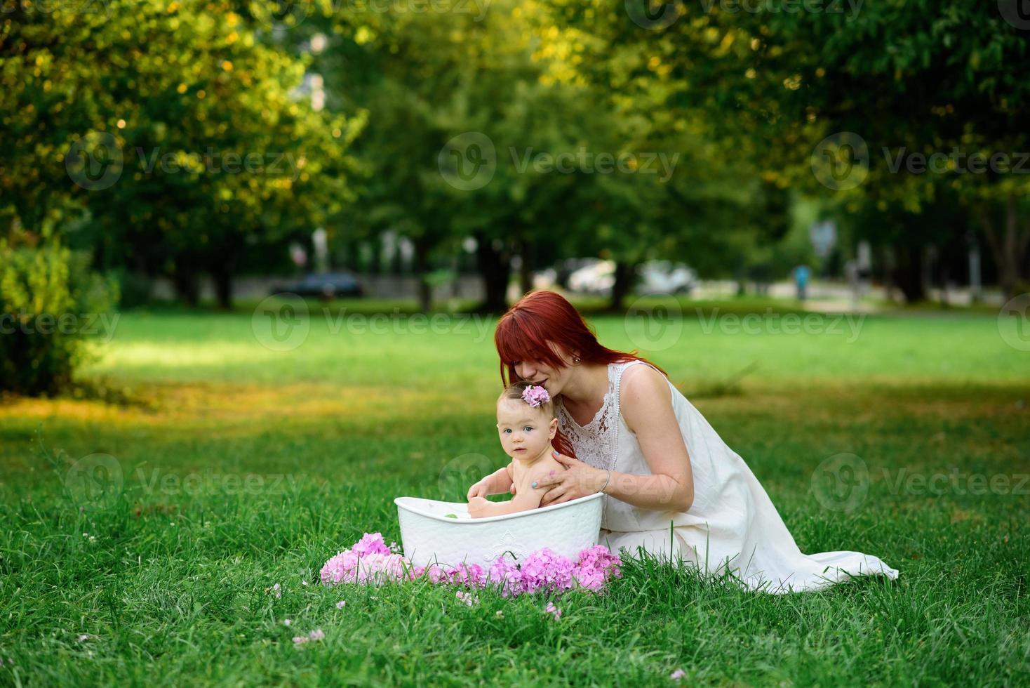 maman aide sa petite fille d'un an à se baigner dans la salle de bain. filmé dans un parc en pleine nature. photo