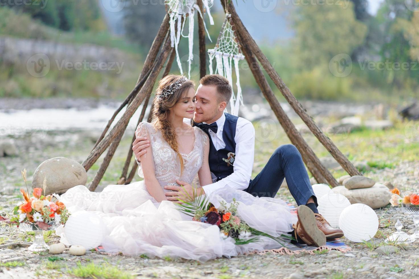 un beau couple de jeunes mariés, un moment heureux et joyeux. un homme et une femme se rasent et s'embrassent dans des vêtements de vacances. cérémonie de mariage de style bohème dans la forêt à l'air frais. photo