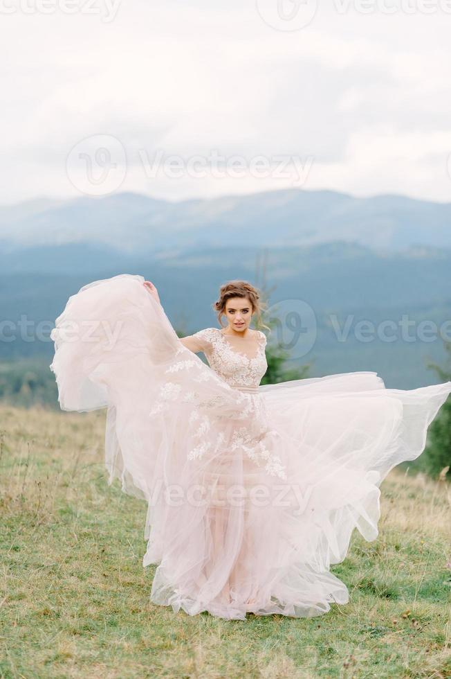 Whirling bride holding voile jupe de robe de mariée à forêt de pins photo