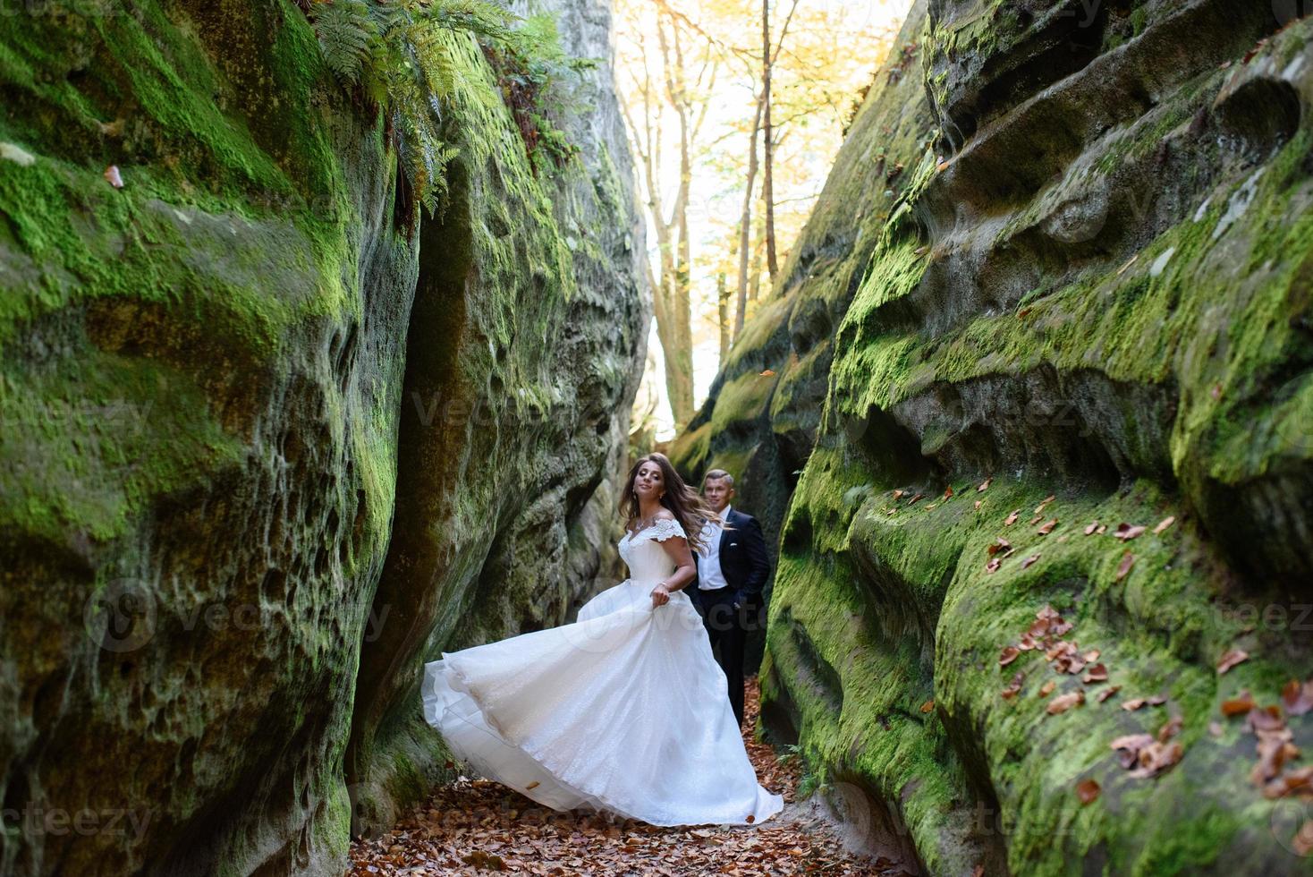 mariés. un couple se promenant dans la belle gorge étroite. la gorge était envahie de mousse verte. les jeunes mariés tournent et courent. photo