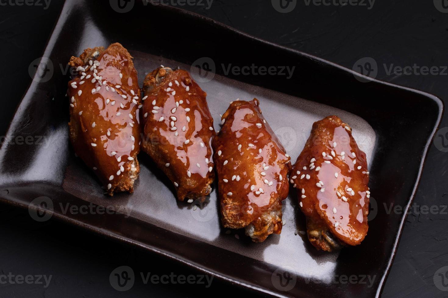 ailes de poulet frites avec sauce coréenne épicée et sucrée garnies de graines de sésame blanc photo