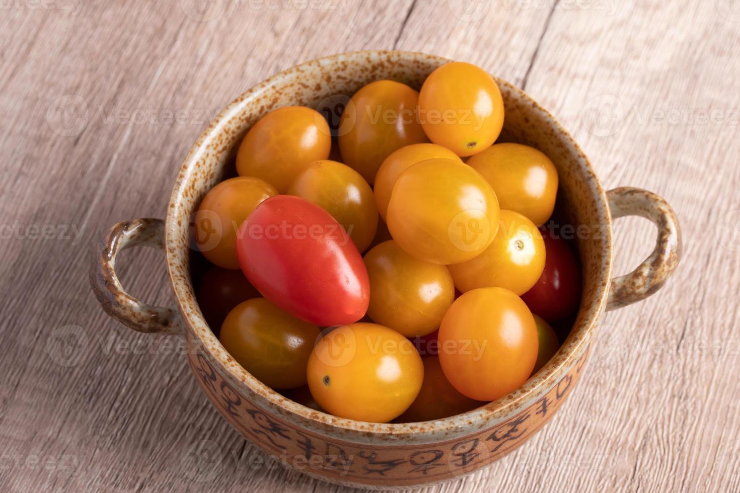 Petites tomates jaunes dans une tasse sur fond de bois photo