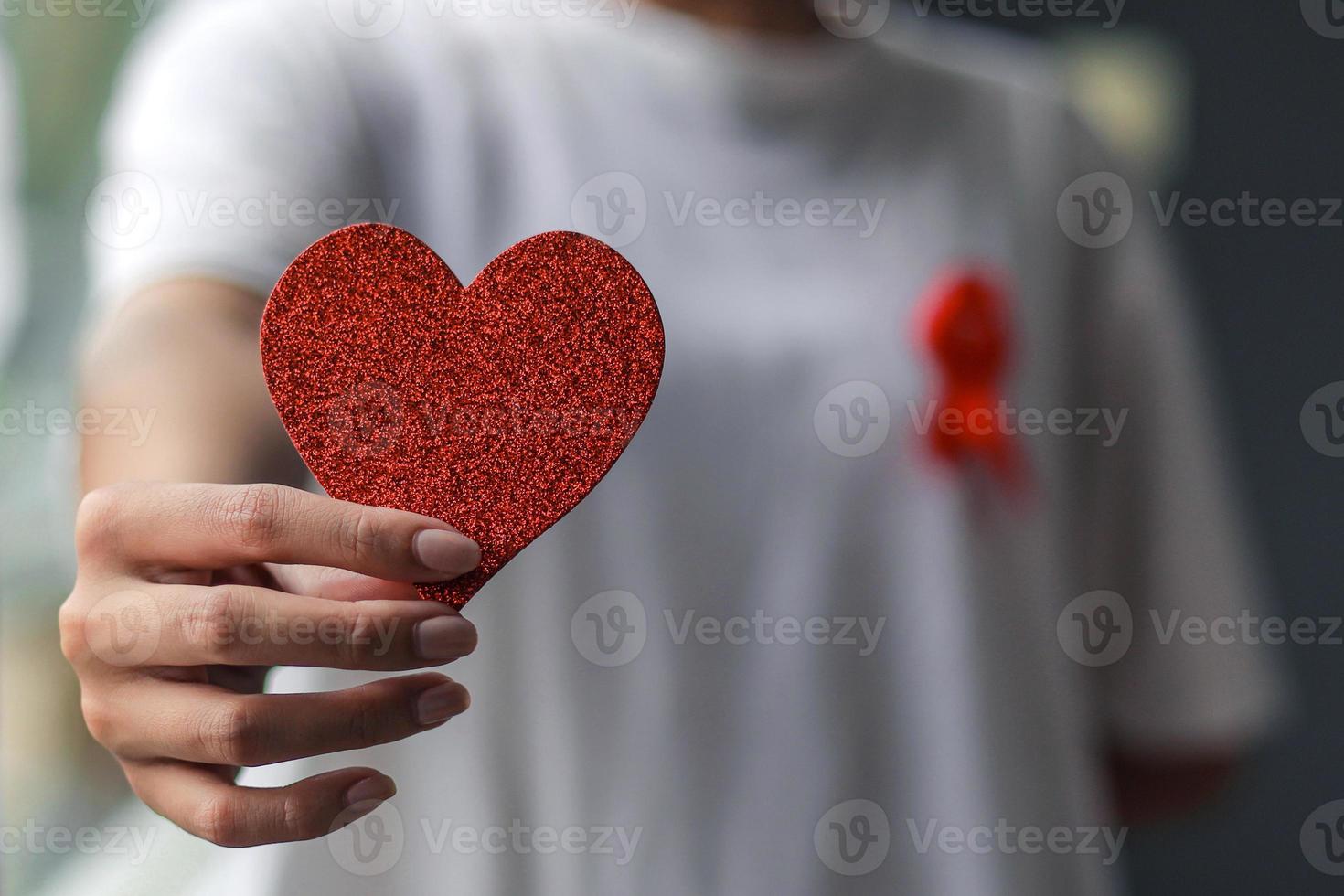 main tenant un coeur rouge en forme d'amour pour la campagne contre le cancer du sein photo