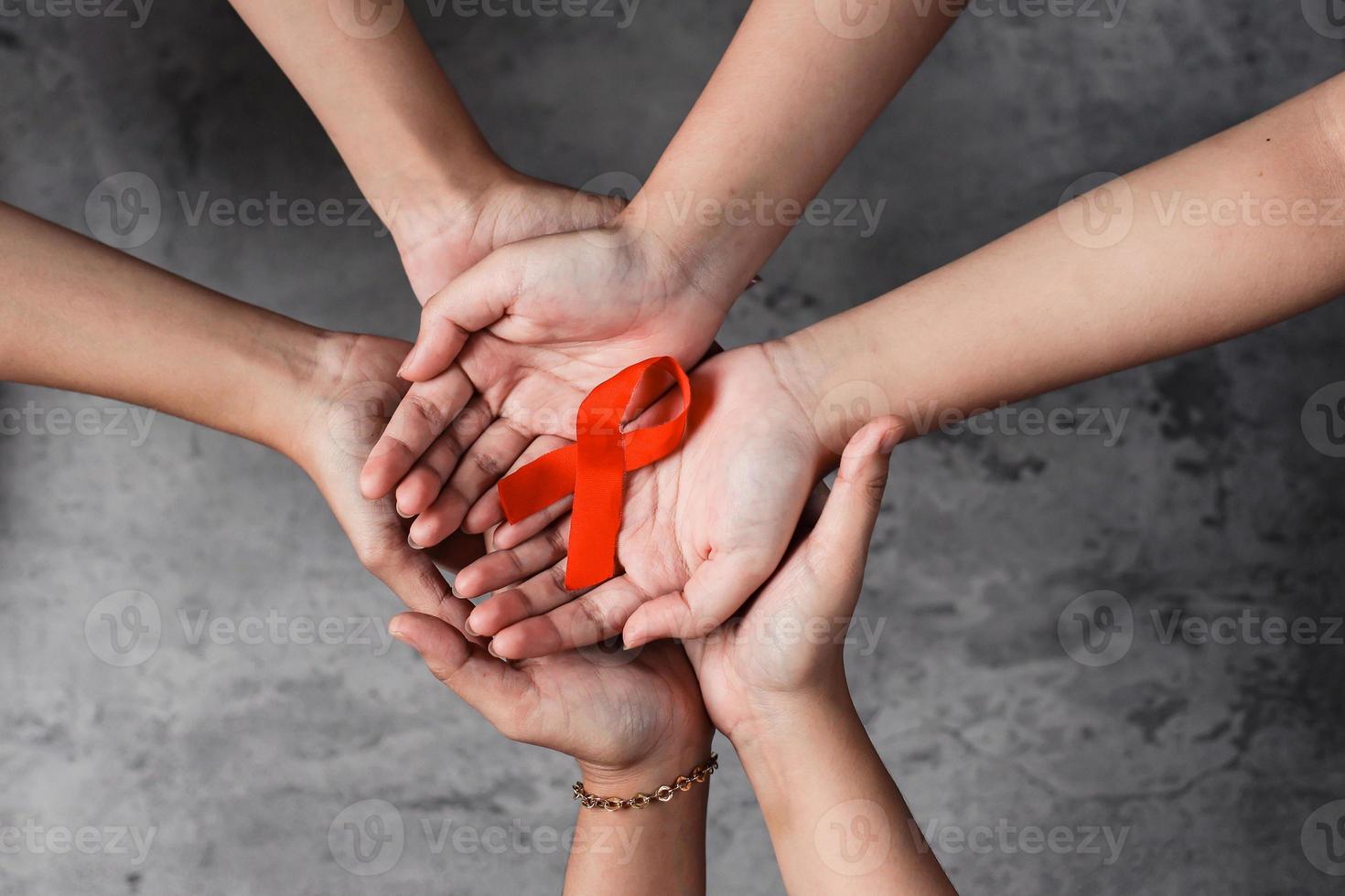 ruban rouge sur les mains pour le sida et le fond de la campagne contre le cancer photo