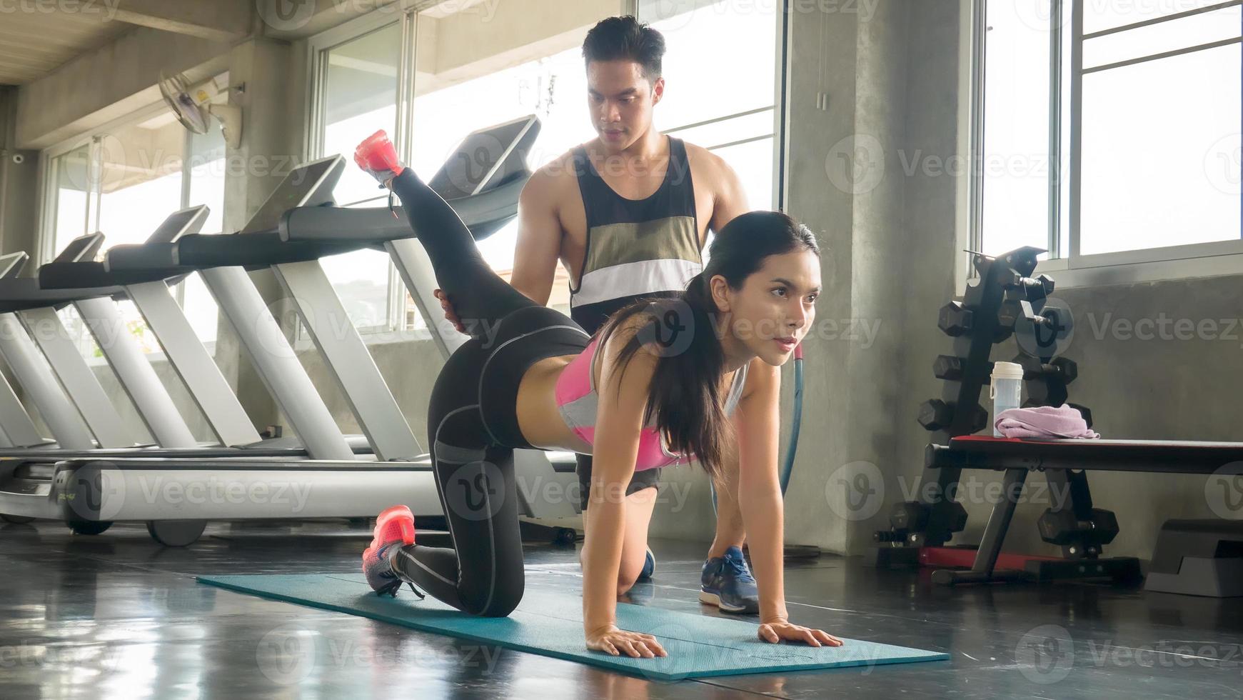 couple d'athlètes sportifs faisant de l'exercice avec une roue à rouleaux abs pour renforcer leurs muscles abdominaux dans la salle de sport. photo