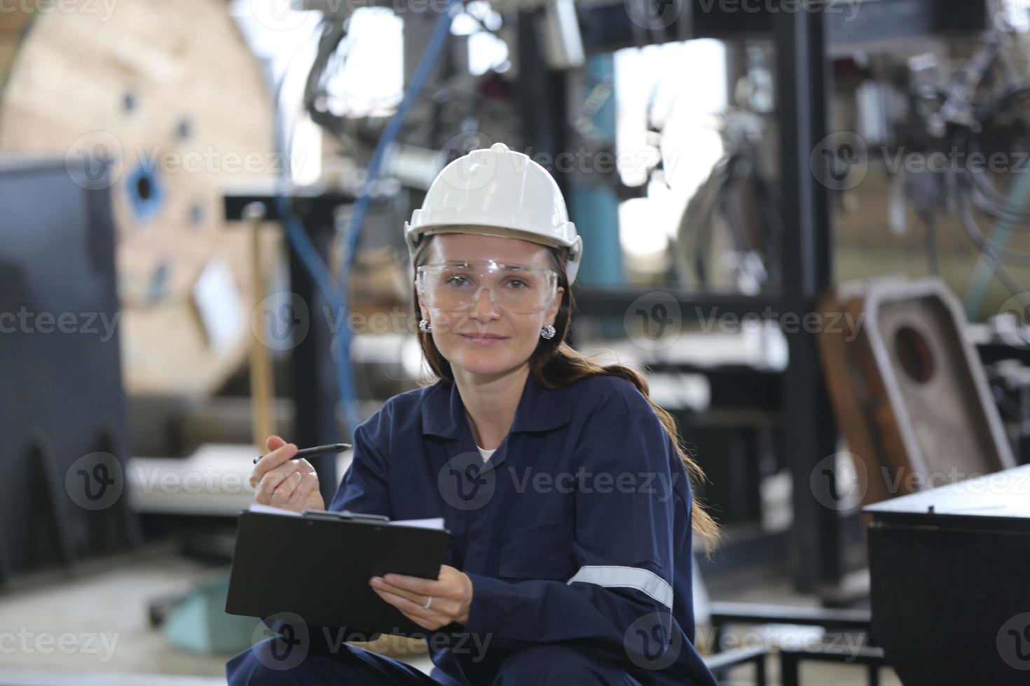 jeune employée professionnelle d'une usine industrielle travaillant avec une pièce de machine, vérifiant et testant des équipements industriels et des bras de robot dans un grand fil électrique et une usine de fabrication photo