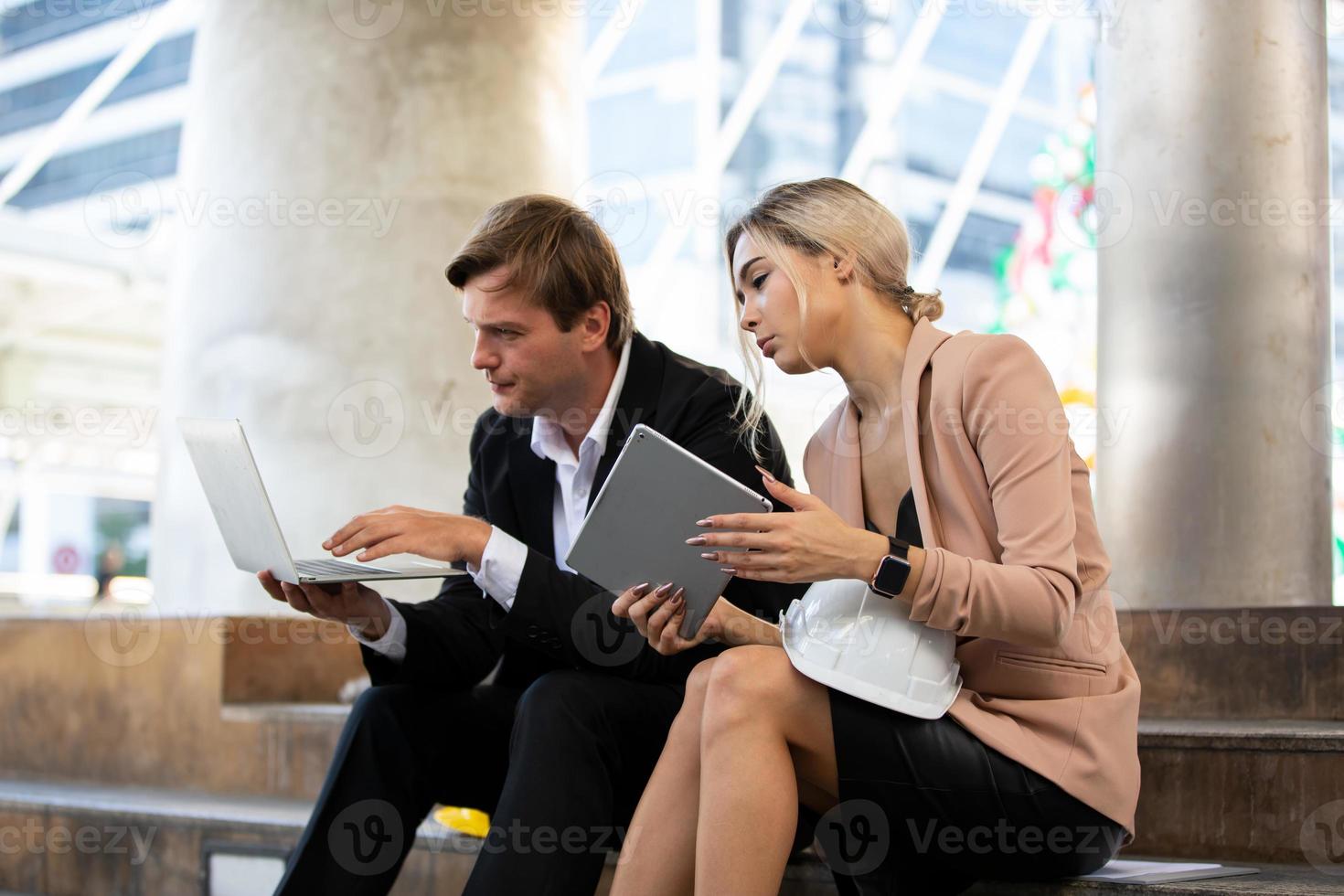 l'ingénieur et la femme d'affaires vérifient le presse-papiers sur le chantier de construction. le concept d'ingénierie, de construction, de vie urbaine et d'avenir. photo