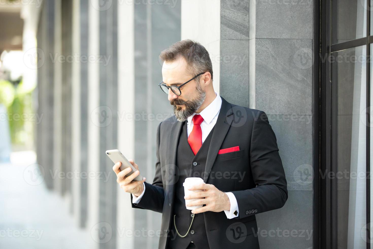 homme d'affaires hipster en costume debout avec une tasse de café près du bureau en plein air photo