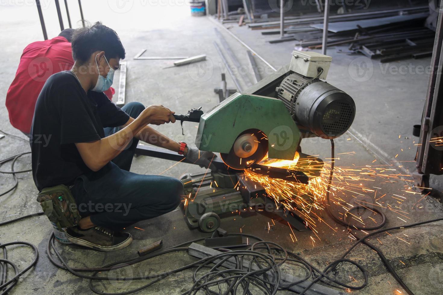 le soudeur a utilisé la meule sur l'acier en usine avec des étincelles, le processus de soudage à l'atelier industriel, les mains avec l'instrument dans le cadre. photo