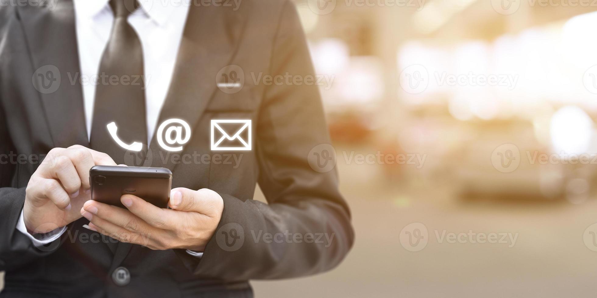 main d'homme d'affaires en appuyant sur une icône de contact sur fond flou de lumières de bureau. photo