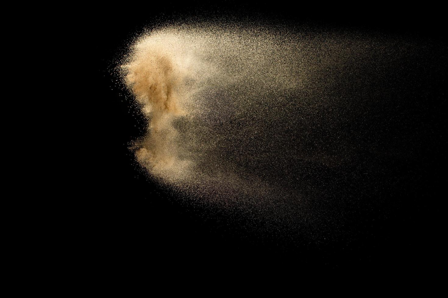 nuage de sable abstrait.éclaboussures de sable de couleur dorée sur fond sombre.vague de mouche de sable jaune dans l'air. le sable explose sur fond noir, jetant le concept de mouvement d'arrêt de gel. photo