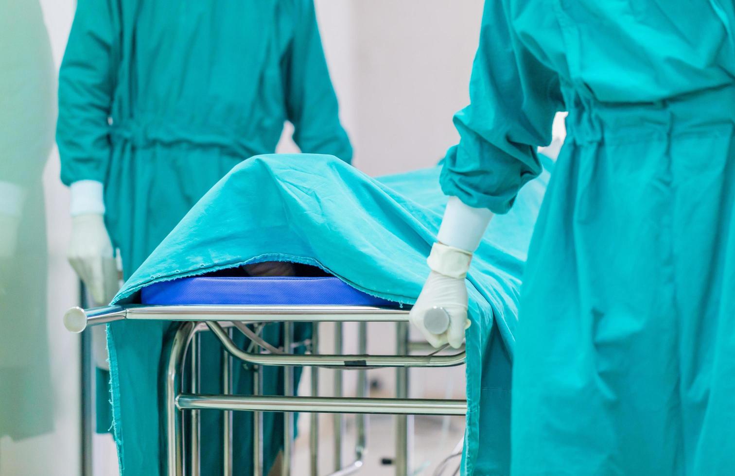 focus sélectif de l'équipe médicale déplaçant le patient en chirurgie dans la salle d'opération de l'hôpital photo