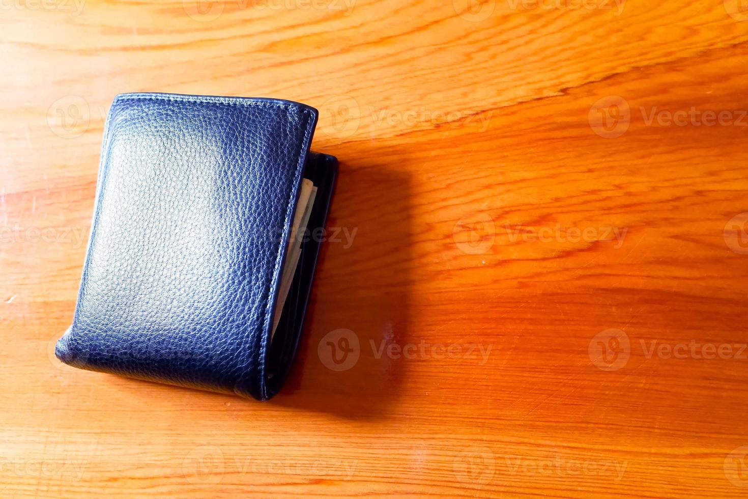 vue de dessus du nouveau portefeuille en cuir véritable noir avec billets et carte de crédit à l'intérieur isolé sur fond de bois orange. photo
