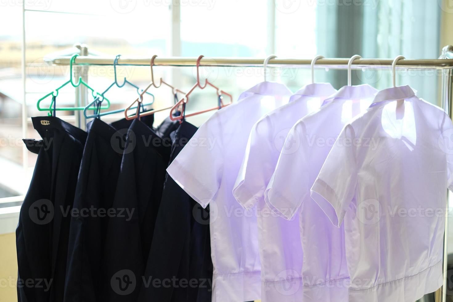 les uniformes des étudiants après le lavage sont suspendus à la corde à linge. chemises blanches et jupes bleues séchant sur un portant à l'intérieur de la maison. concept de retour à l'école. photo