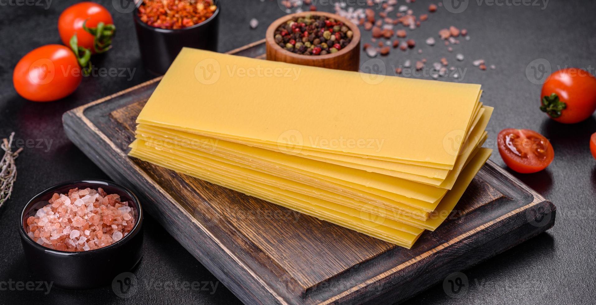 pile de feuilles de lasagne sur fond de béton foncé. ingrédients pour les lasagnes photo