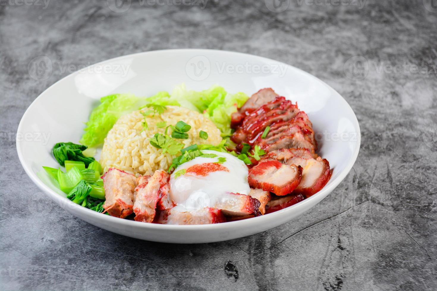 porc rouge grillé et porc croustillant en sauce rouge, servis avec du riz et des légumes sur une assiette blanche. photo