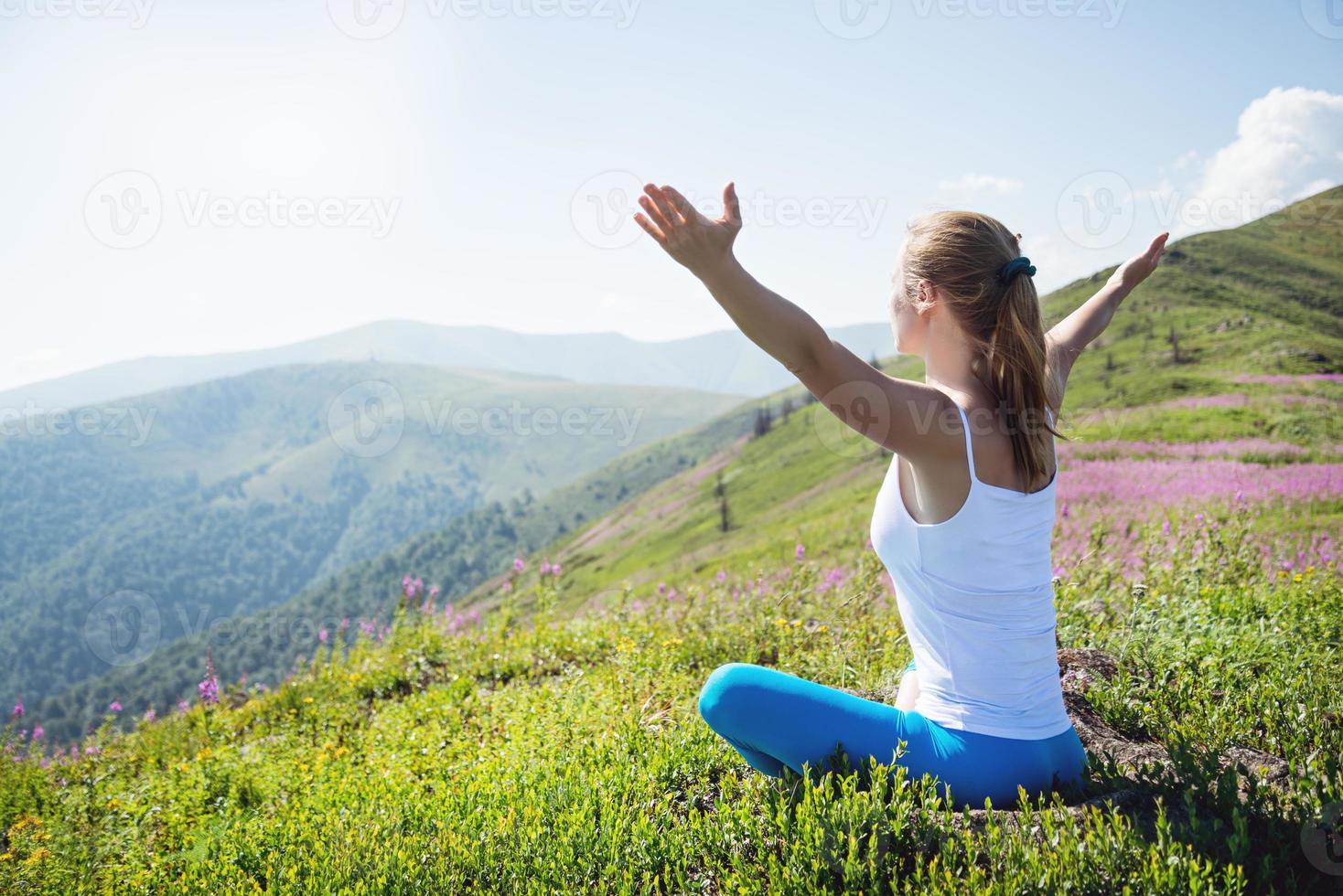 jeune femme médite au sommet de la montagne photo