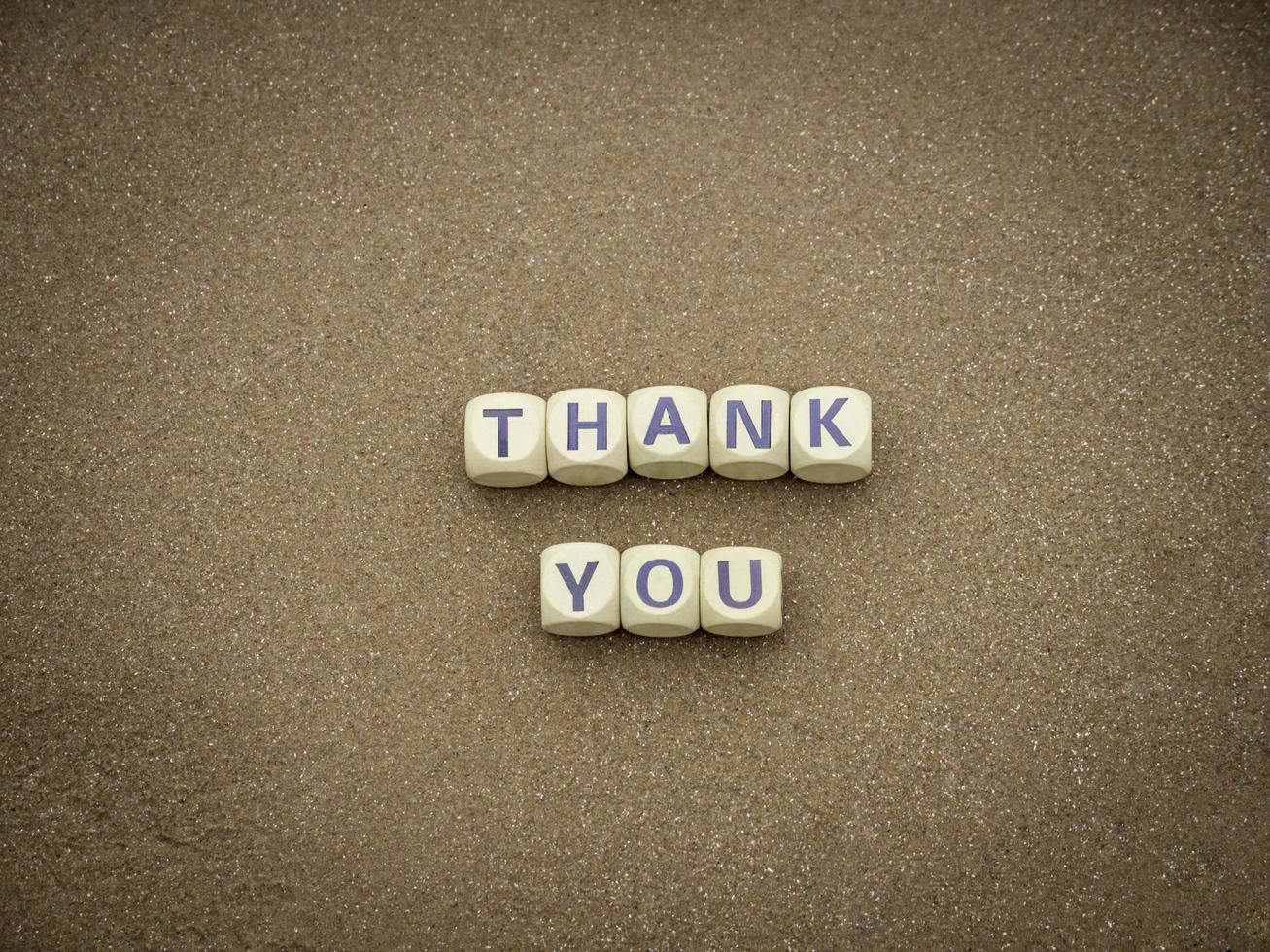 merci libellé cube en bois sur le sable propre de la plage avec un ciel bleu le matin. gratitude, beau concept de carte. photo