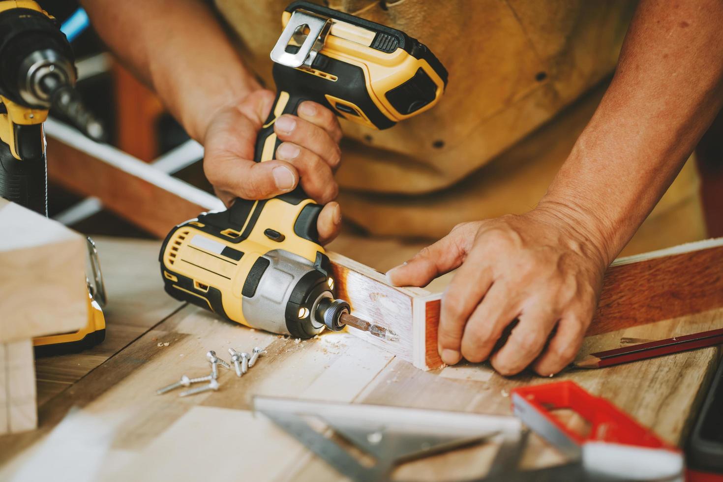 charpentier utiliser une perceuse sans fil enfoncer la vis sur le bois, le fabricant de bricolage et le concept de menuiserie. mise au point sélective photo