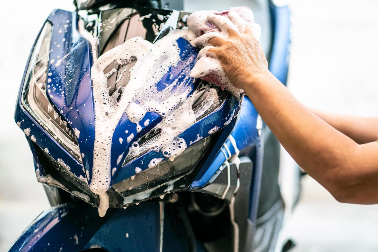 scooter de lavage de motards. nettoyage de la moto avec une éponge ou un chiffon doux au garage, réparation et entretien du concept de moto. photo